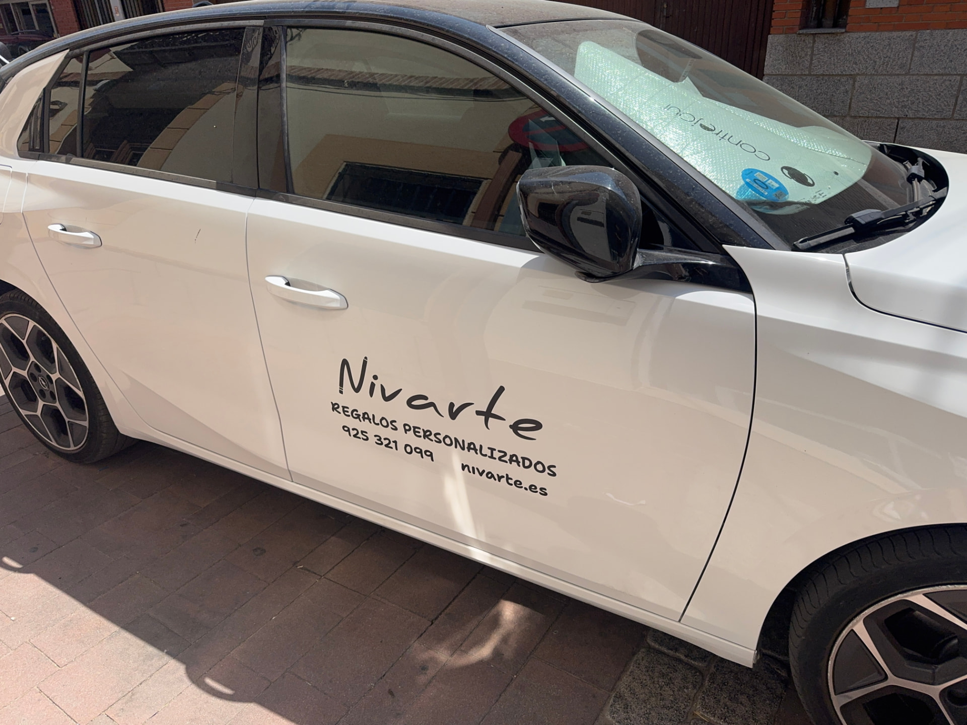 Coche blanco con rotulación de Nivarte en la puerta